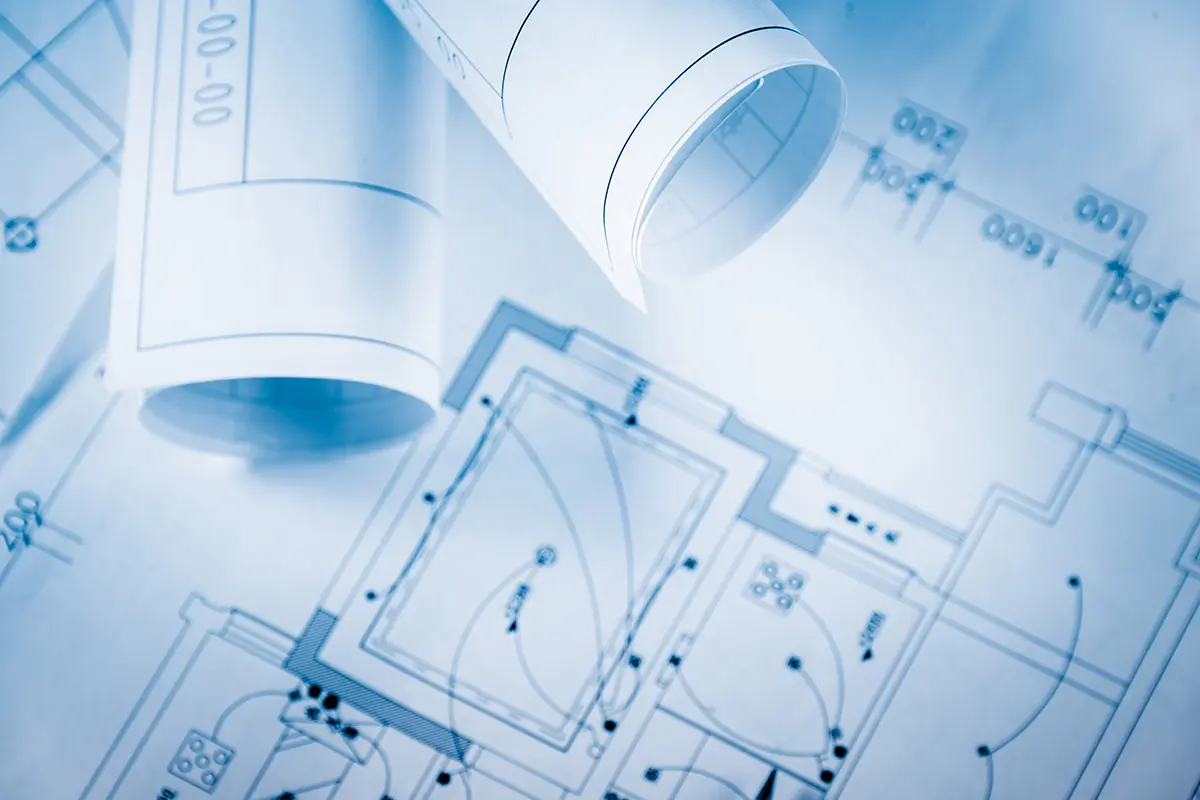 Blaupausen und architektonische Zeichnungen liegen auf einem Tisch ausgebreitet.
