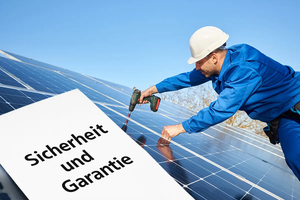 Ein Mann trägt blaue Overalls und einen Helm und montiert eine Solaranlage.