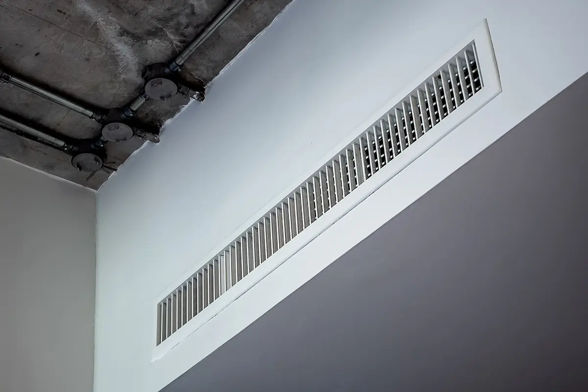 Weißer Deckenbereich mit einem Lüftungsgitter in der Mitte